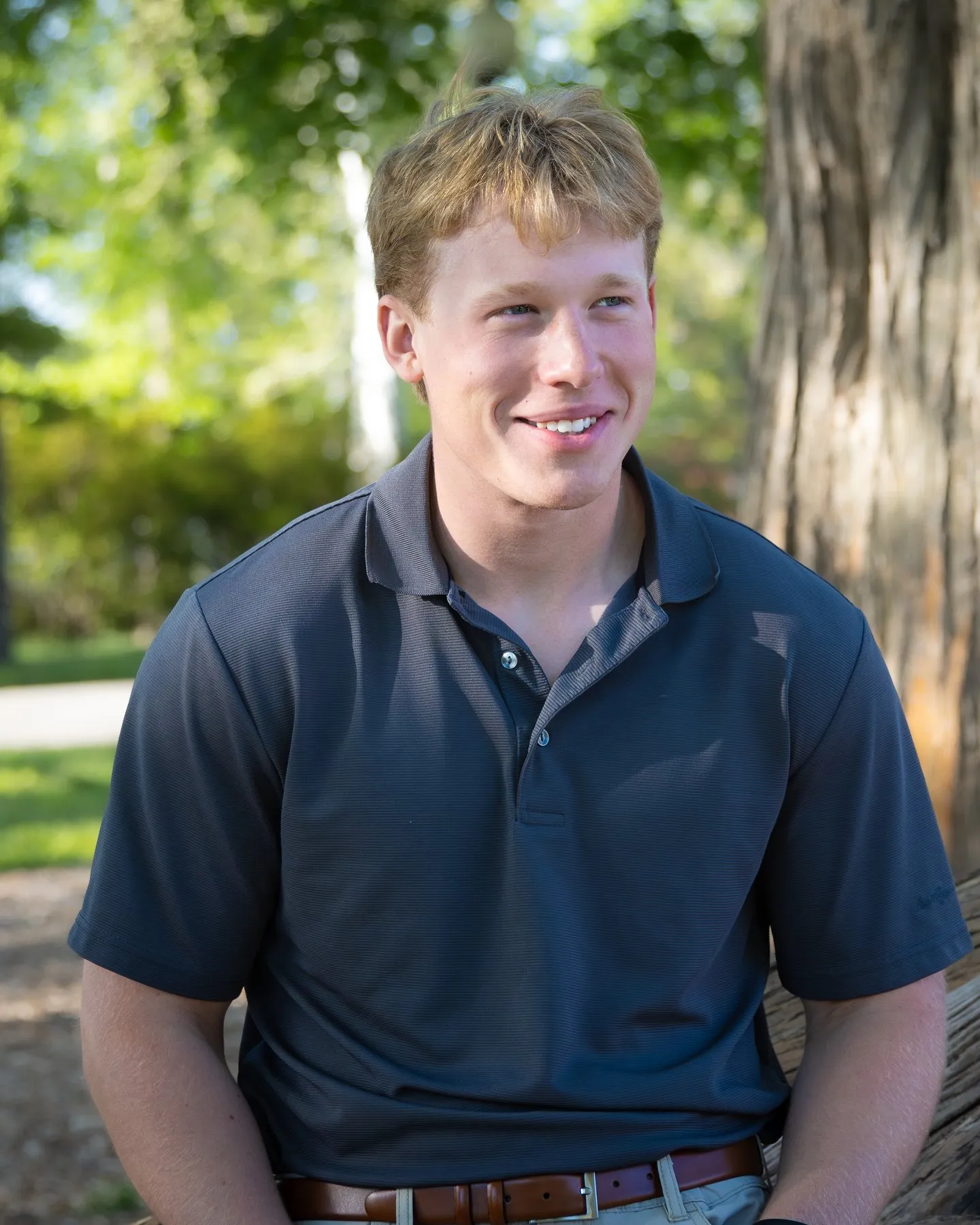 Laben D. Byers smiling outdoors under the trees, wearing a navy polo shirt.